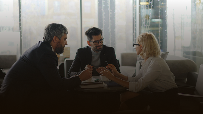 Three people in discussion at a table in a modern lounge